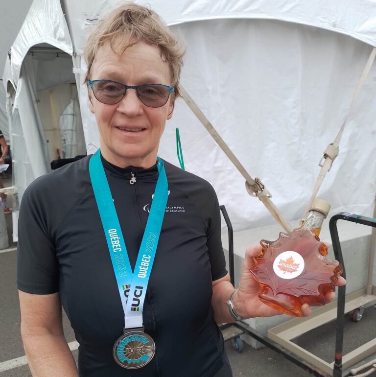 Smiling Eltje wears silver medal and holds large bottle of maple syrup