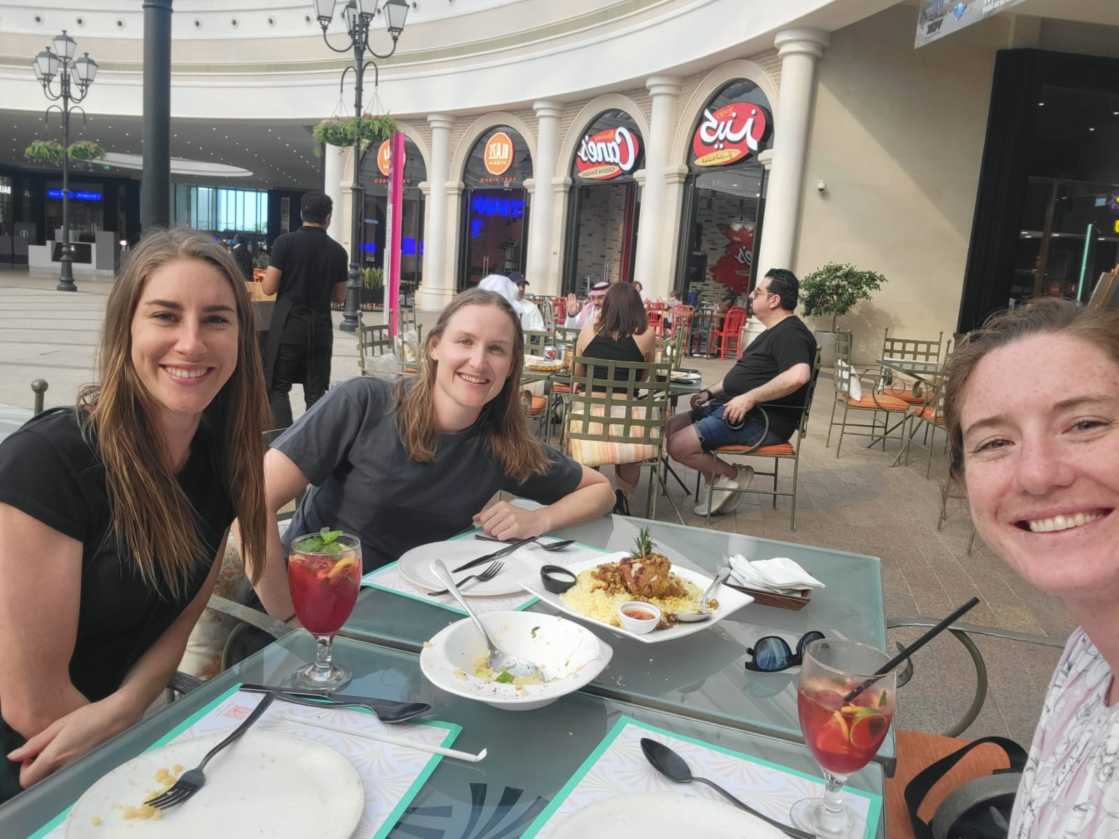 Selfie of three caucasian women at an outdoor restaurant in an urban setting