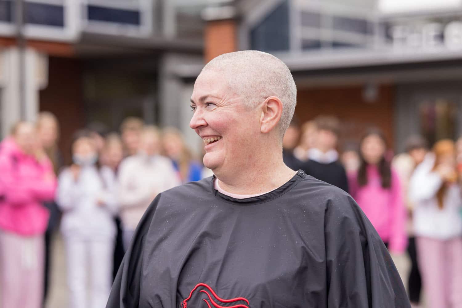 Jo laughs after having her head shaved. Students in background.