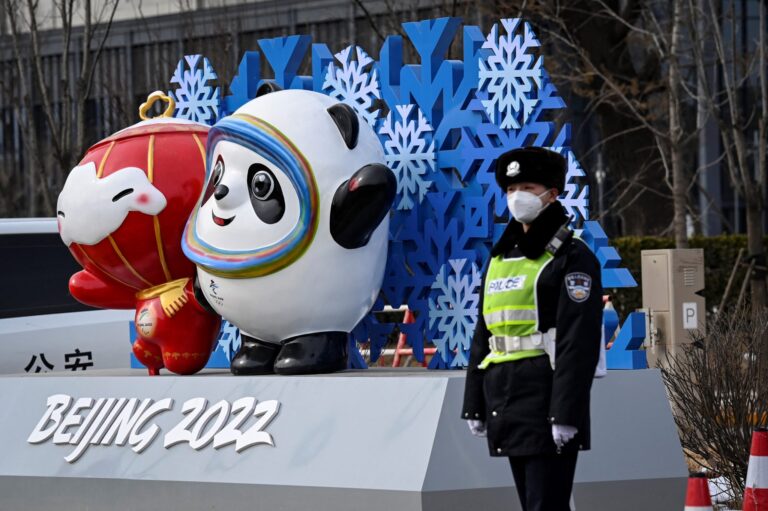 A police officer stands next to an installations displaying the mascots for the Beijing 2022 Olympic and Paralympic Winter Games