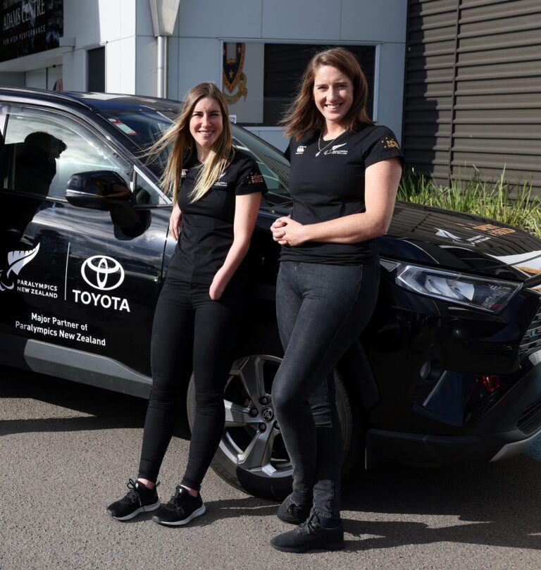 Nicole Murray and Anna Taylor lean against a PNZ branded car