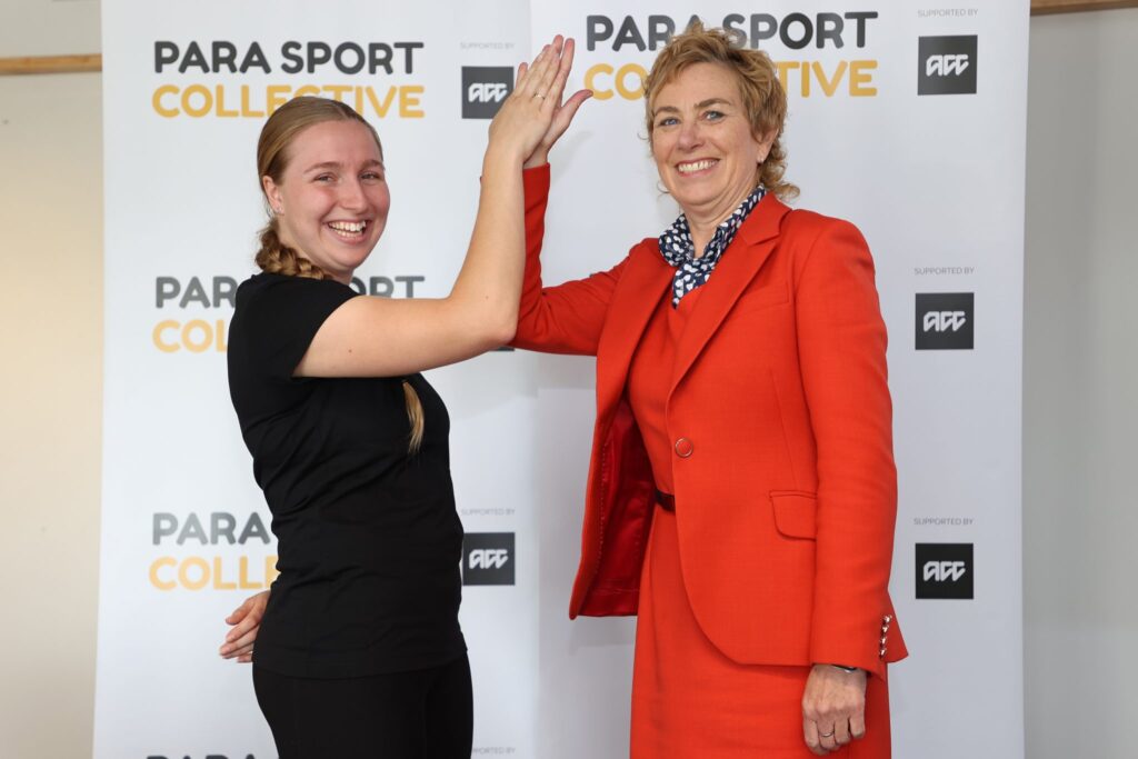 Para athlete Siobhan Terry high fives ACC CE Megan Main in front of a banner with Para Sport Collective on it