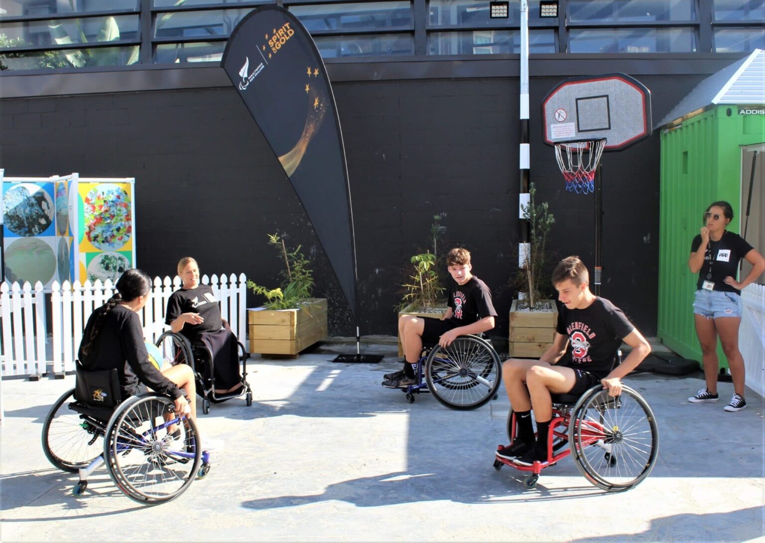 4 kids playing wheelchair basketball outdoor