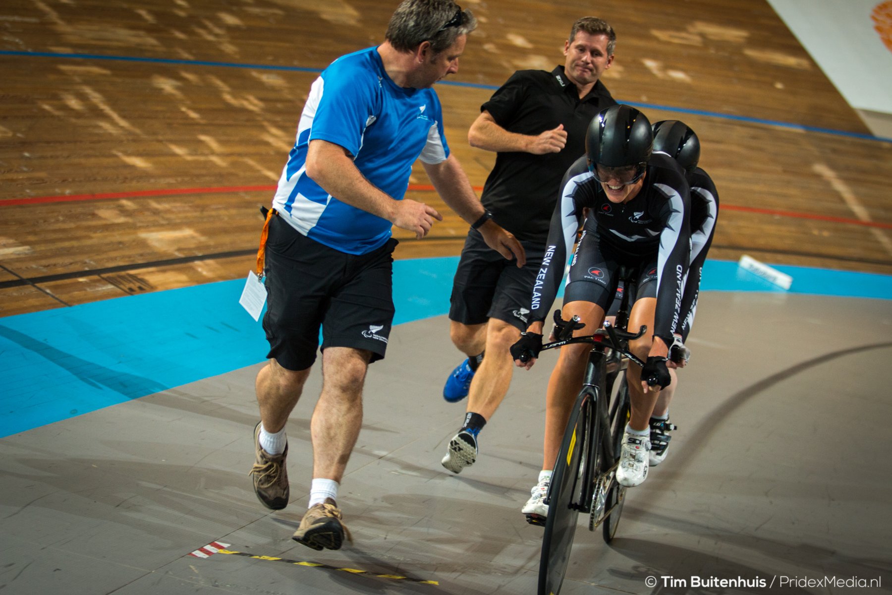 Brendon and another staff member run alongside a tandem bike at the velodrome