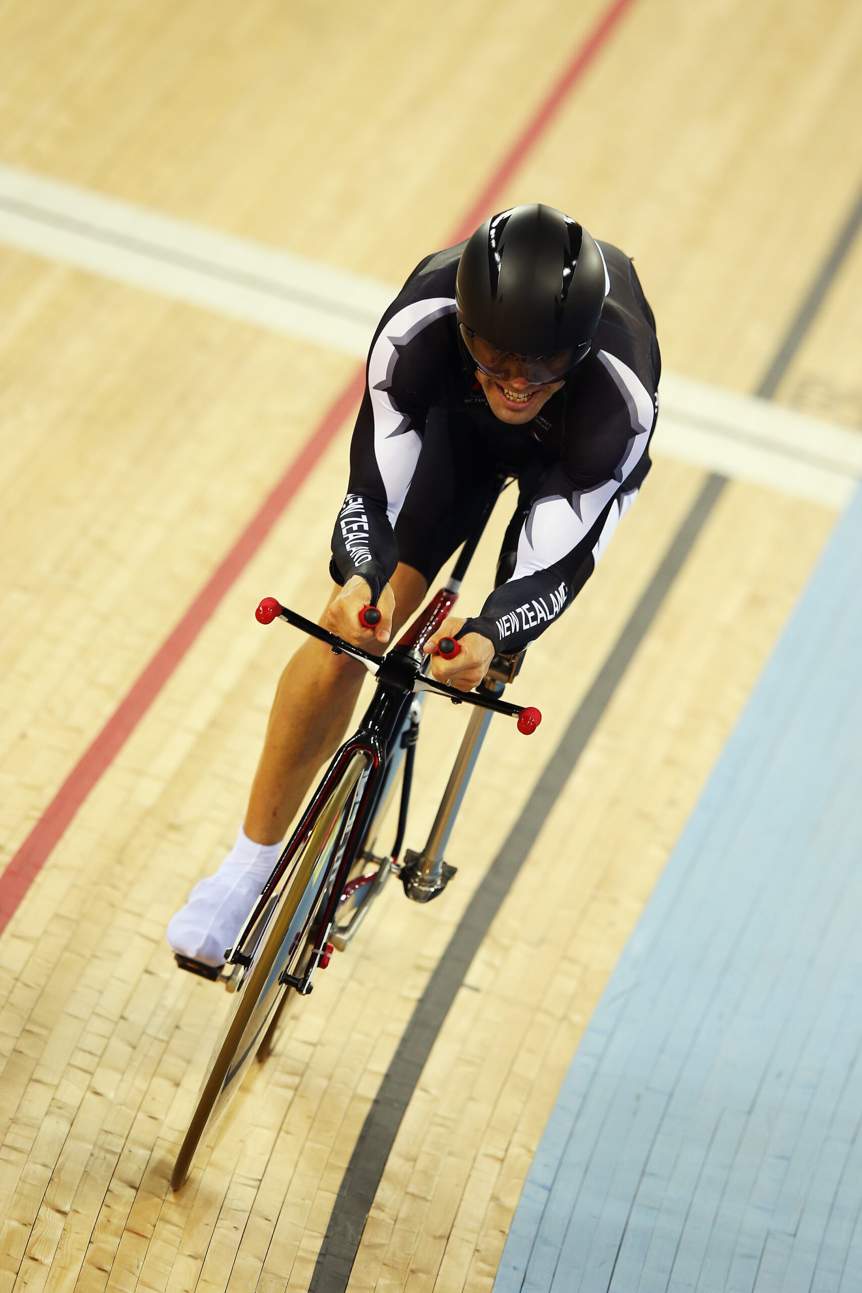 Nathan grits teeth as he cycles fast on velodrome track