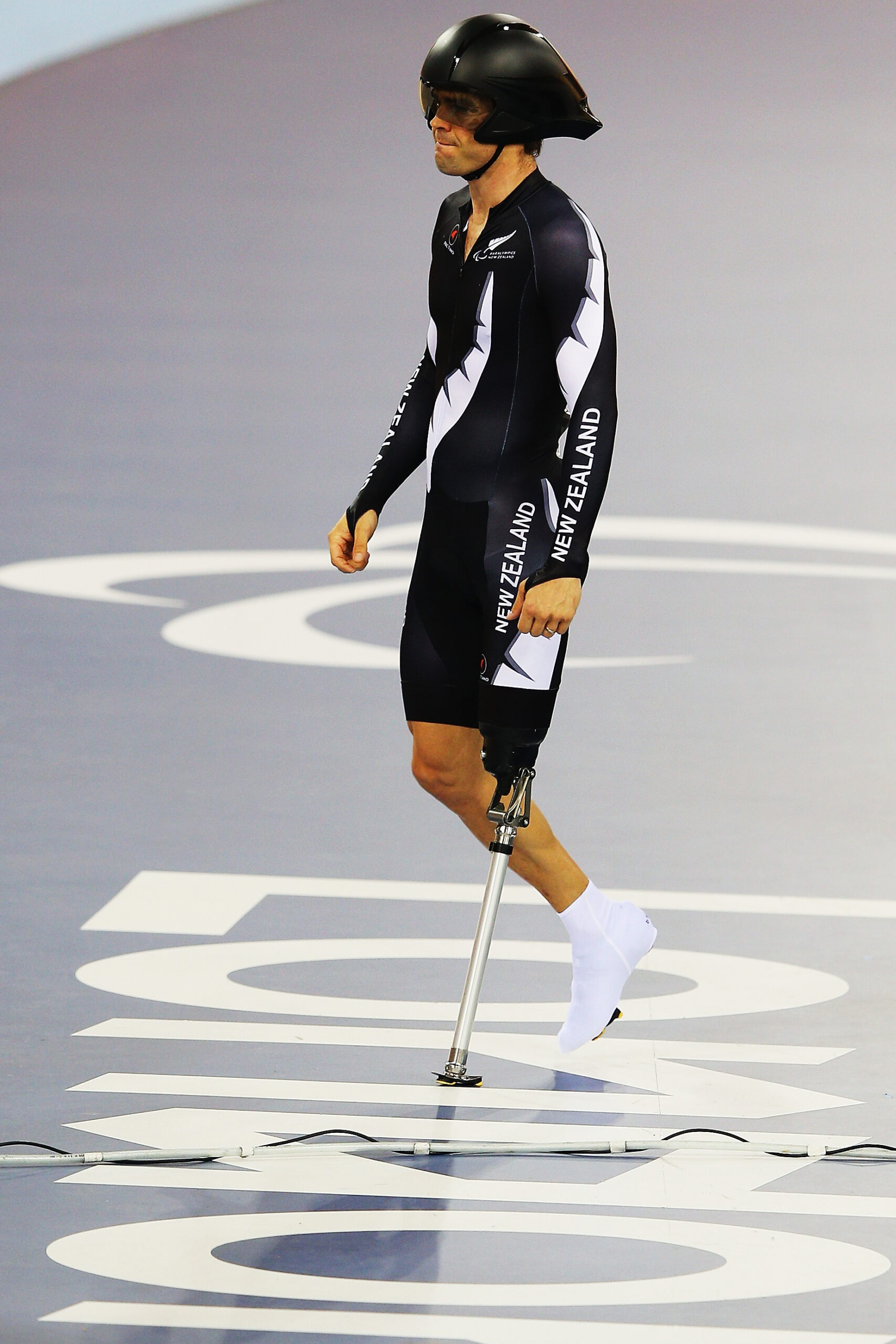 Nathan wearing helmet and cycling prosthetic walks over London 2012 on floor