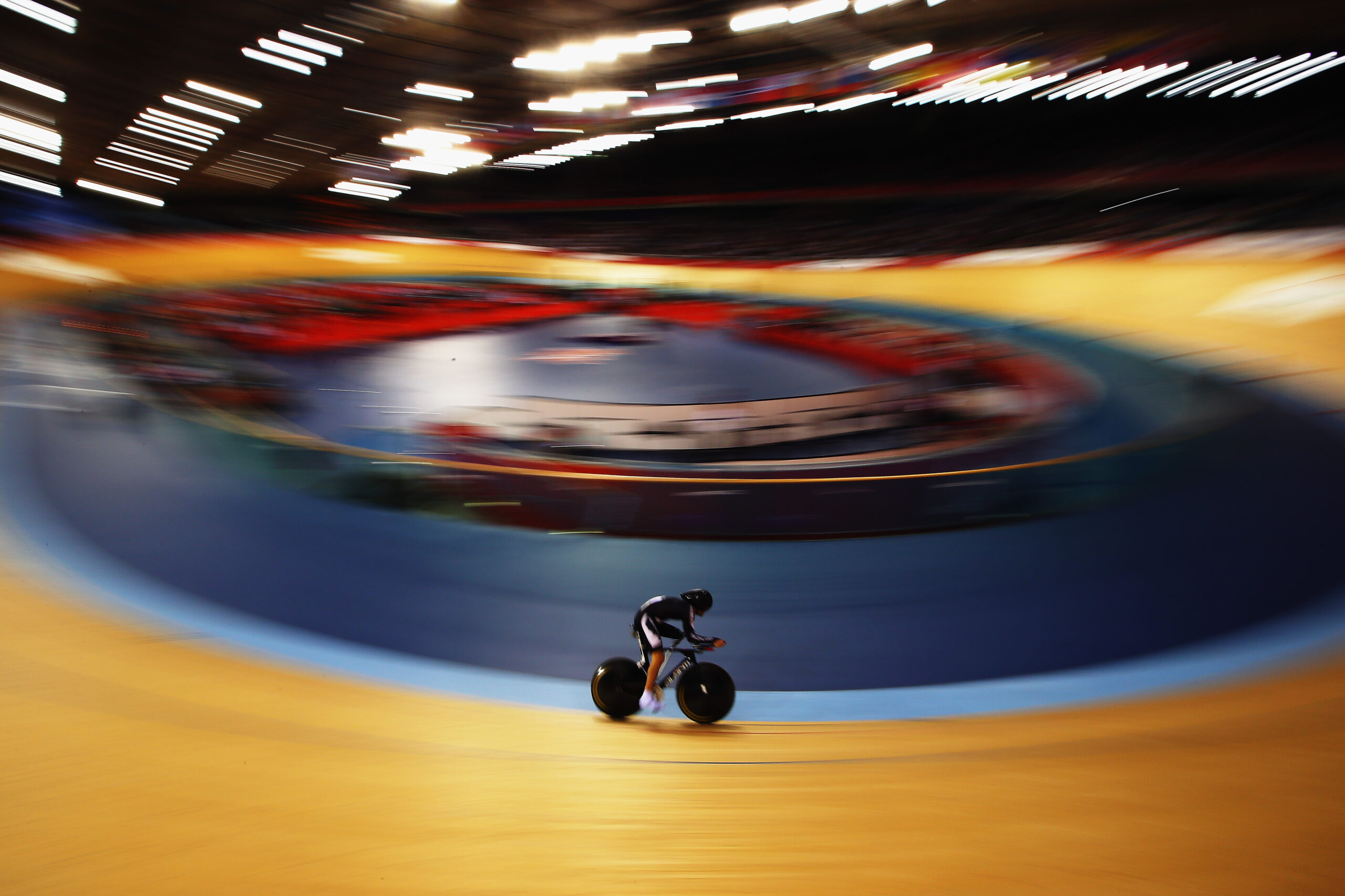 wide shot of Nathan alone on the velodrome track with speed blur