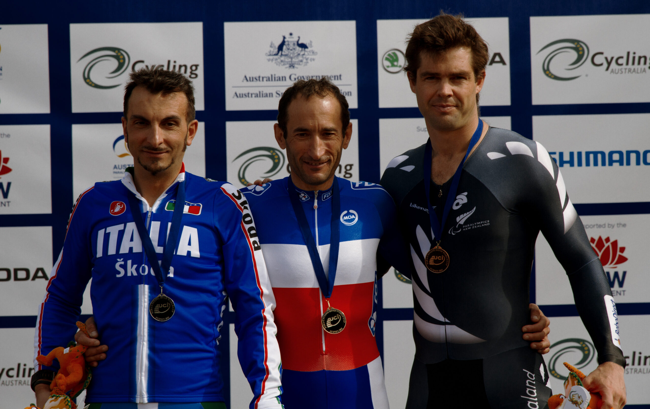 Three men cyclists stand on the podium