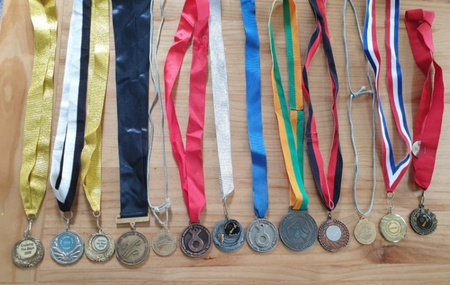 13 medals exposed on a table with their coloured ribbons