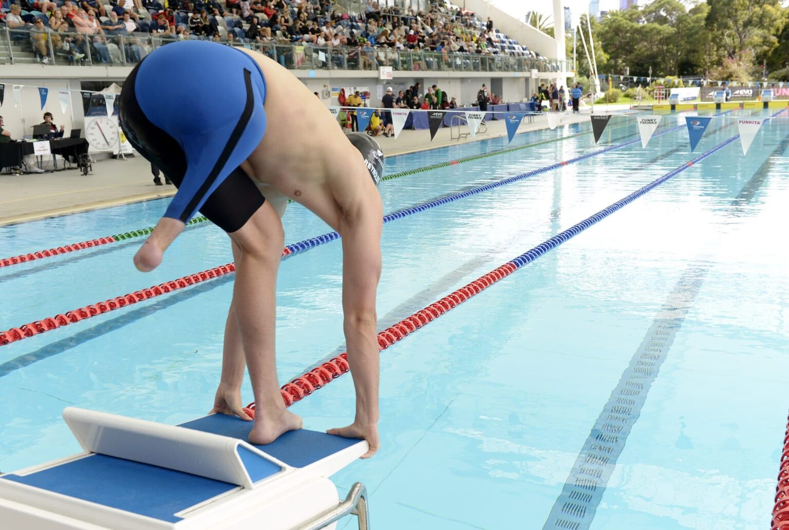 Para swimmer with a lower limb deficiency ready to dive in the swimming pool