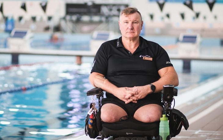 Double leg amputee in a chair beside swimming pool