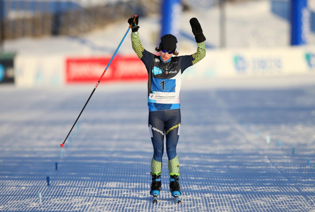 cross-country Para skier crosses the line with hands in the air