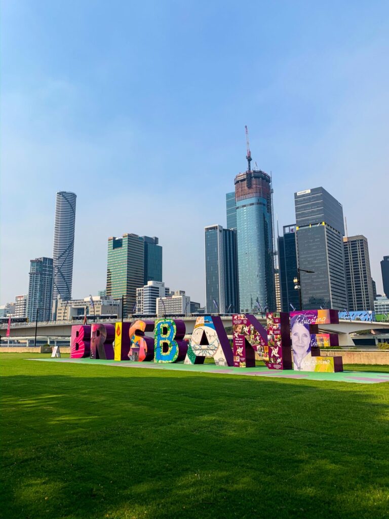 Colourful "Brisbane" sign in front of city skyline.