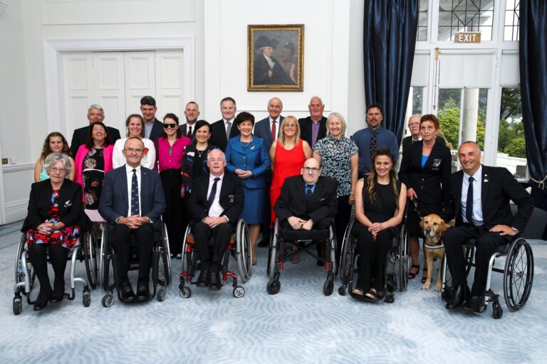 group shot of 18 NZ Paralympians in formal dress in elegant historic interior setting