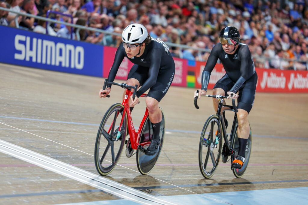 Two cyclists in black race on the velodrome track