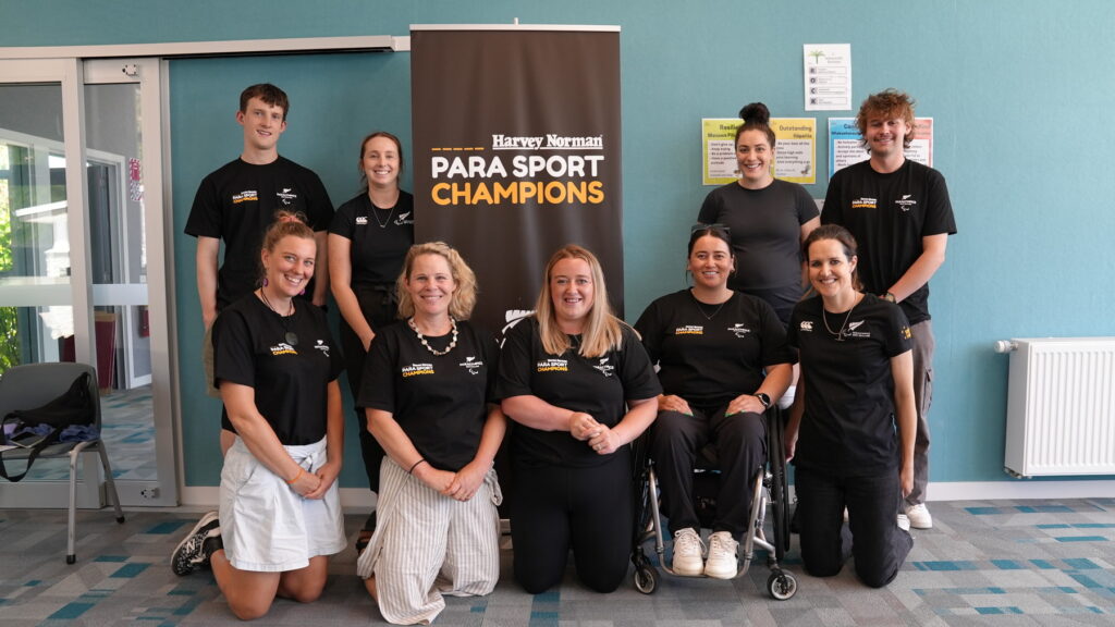 9 Paralympians, Para athletes and organisers stand for a photo in front of a Para Sport Champions banner