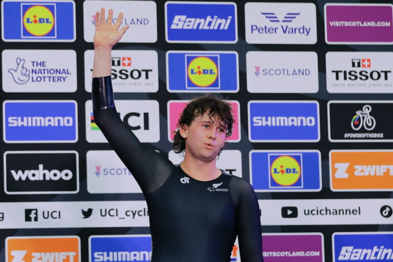 Devon waves from podium, looking like he's just finished a hard race
