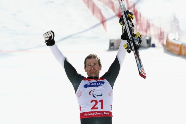Adam Hall throws his hands in the air in celebration at the victory ceremony for the Para alpine skiing slalom standing at PyeongChang 2018.