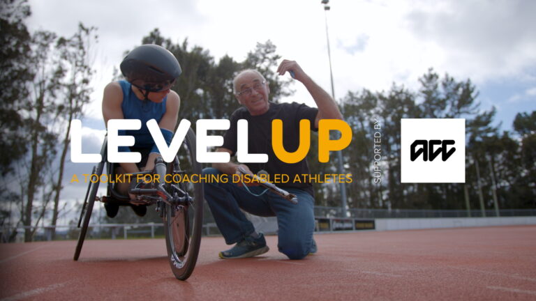 A coach with an athlete in a racing wheelchair, outdoors on the track. LevelUp logo overlaid.