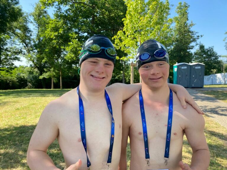 Luka and Joseph outdoors in swim gear and Virtus lanyards, giving thumbs up