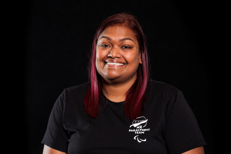 Portrait of Neelam O'Neill in front of a black backdrop. She wears a black NZ Paralympic Team branded t-shirt.