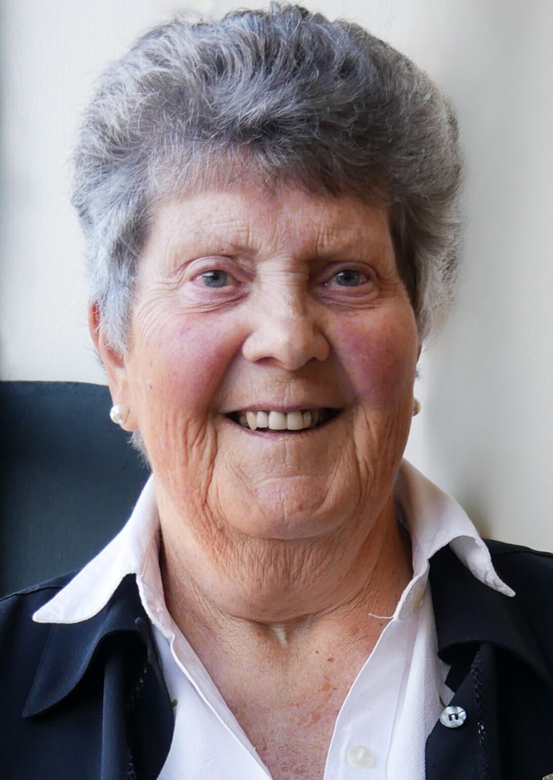 head and shoulders portrait of smiling pakeha woman in her 70s with short thick grey hair