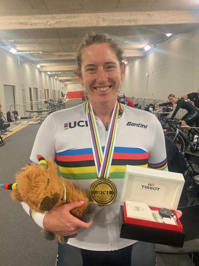 Anna with mascot and medal, wearing rainbow jersey