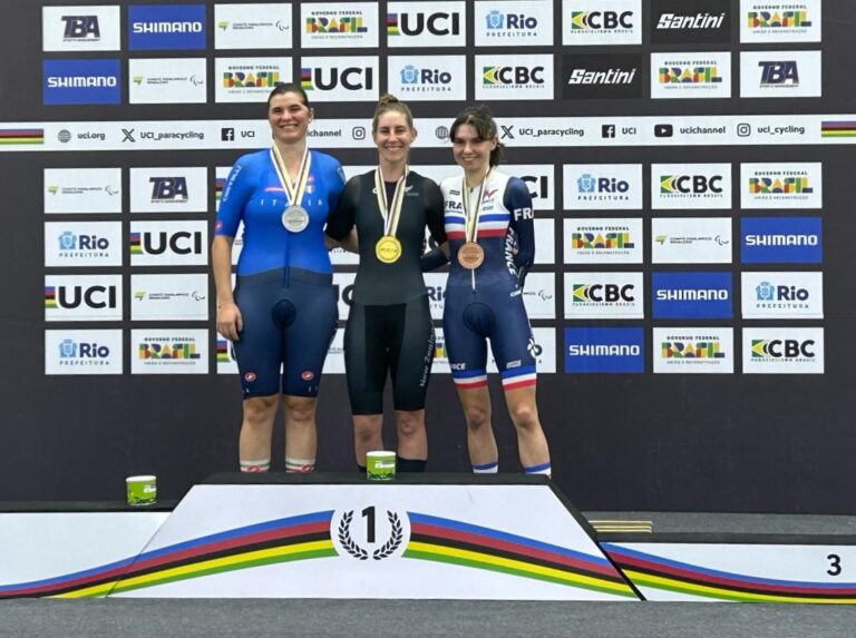Nicole wears the gold medal and smiles from the podium with the other medallists