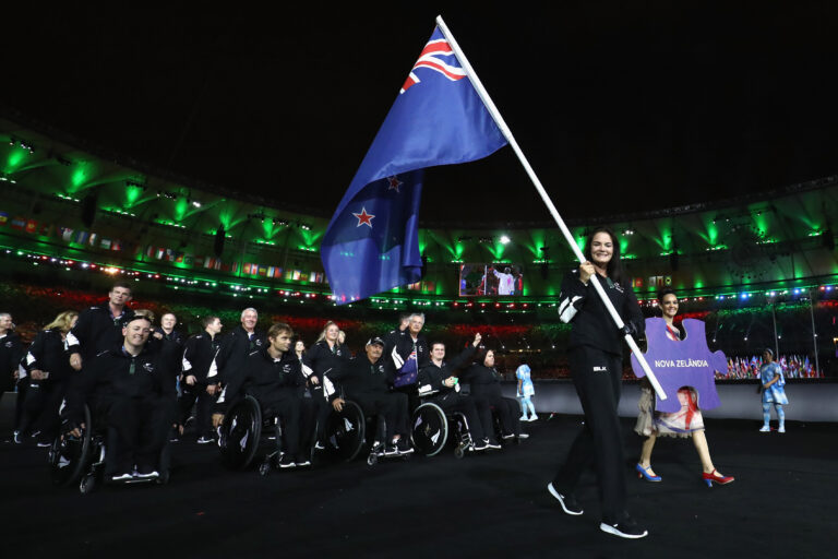 Holly Robinson leads New Zealand Paralympic team, holding a New Zealand flag