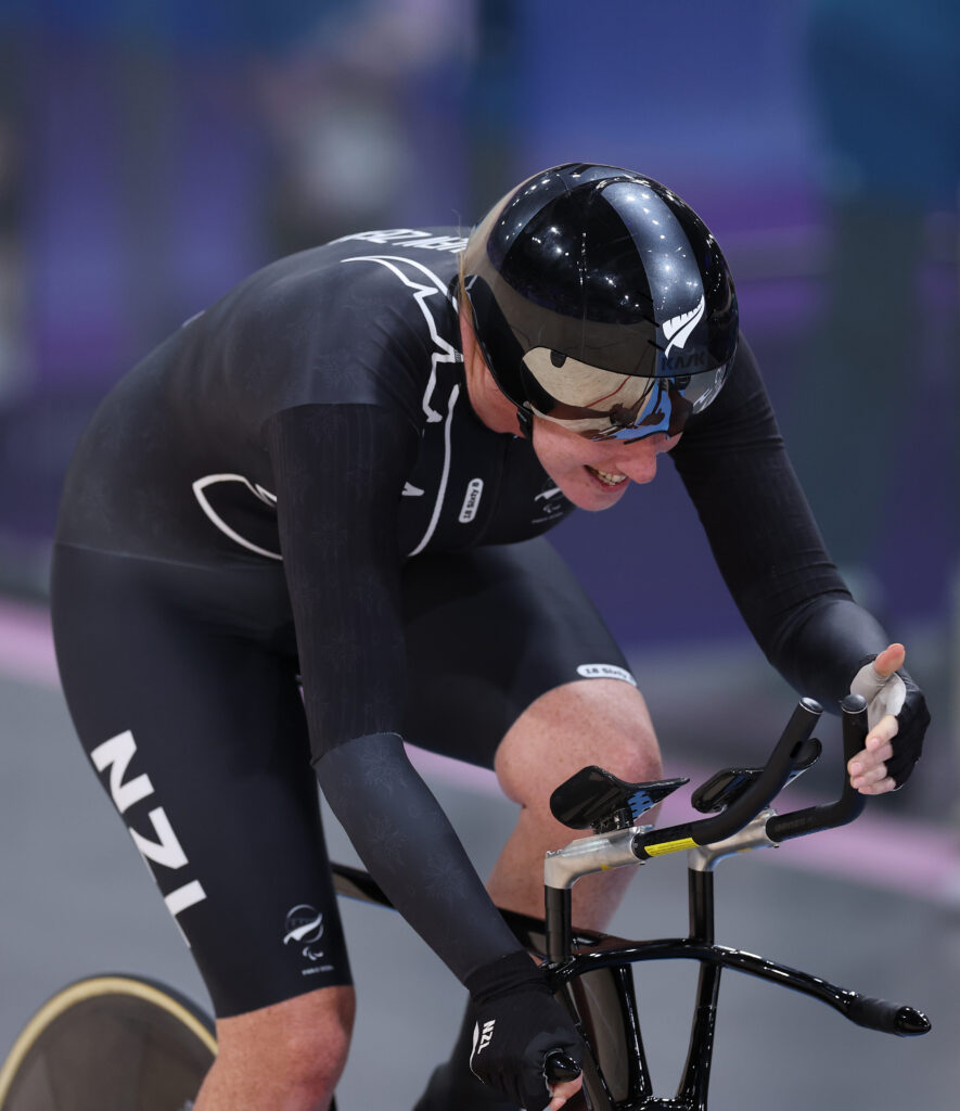 Paralympian Anna Taylor on a black bike wearing a black race suit and helmet with a white silver fern