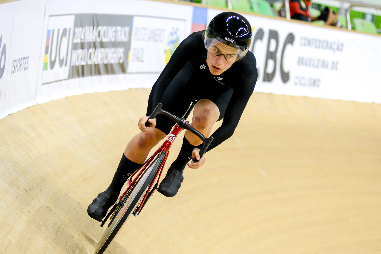 Ben Westenberg races in cycling on a velodrome representing New Zealand in black NZ branded uniform.