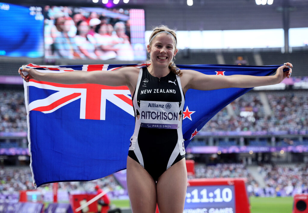 Danielle Aitchison celebrates after the Women's 100m Final T36 winning silver with NZ flag around her shoulders