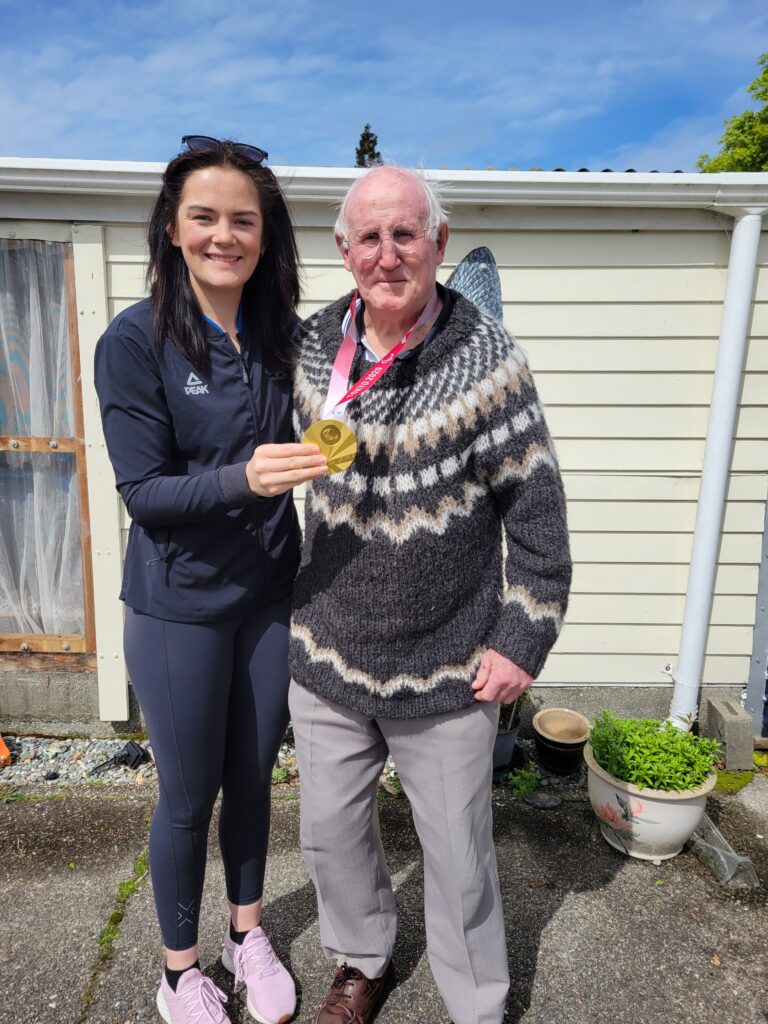 Holly Robinson holds her Tokyo 2020 Paralympic Games gold medal with first coach Danny Spark.