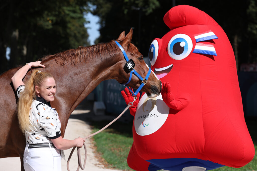 Louise Duncan pets horse Showcase BC alongside the Paris 2024 Paralympic Games mascot, the Phryges.