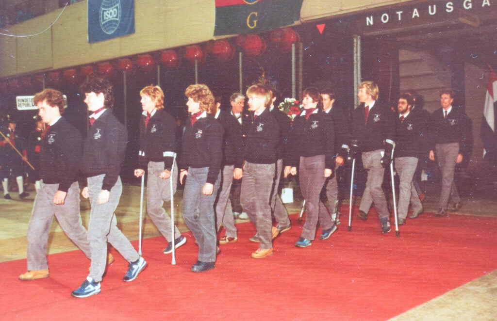 The NZ Team enter the opening ceremony of the 1984 Innsbruck Winter Games. L-R: Mark Edwards, Viv Gapes, Patricia Craig, Lorraine Philip, (Concealed), Craig Philip, (concealed), Kay Shears, Martin Clark, Denis Butler, (concealed), Chris Orr, (concealed), David Boyd