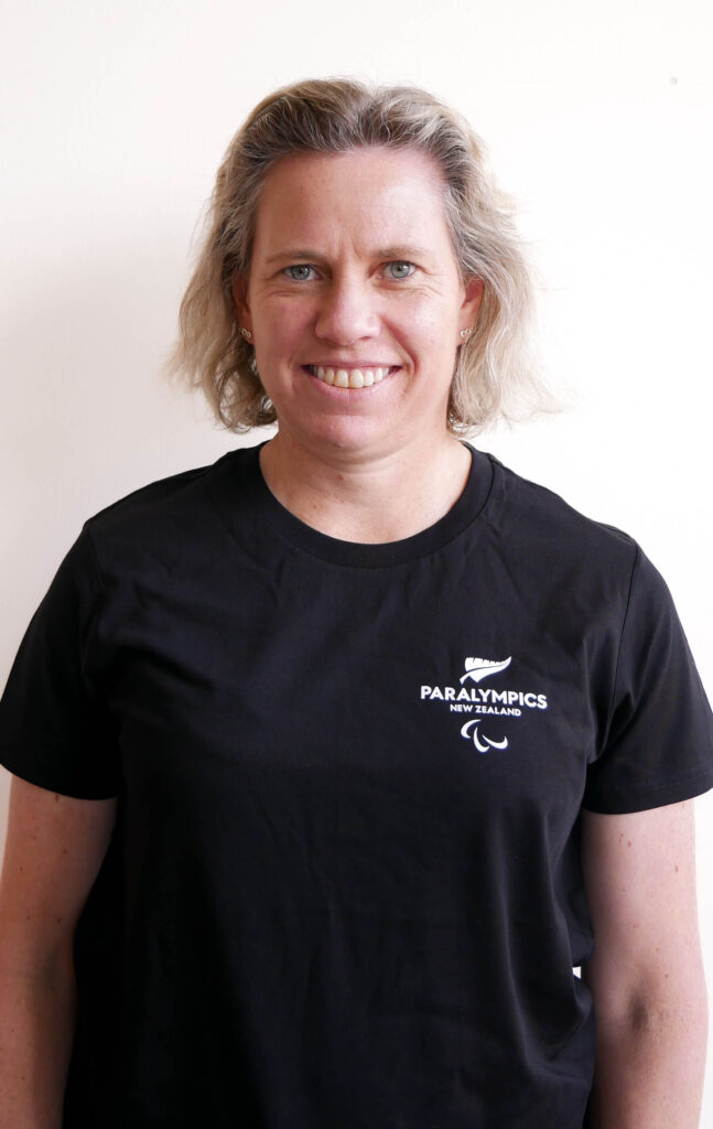Portrait of Kristin Farell infront of a white backdrop. She wears a Paralympics New Zealand shirt.