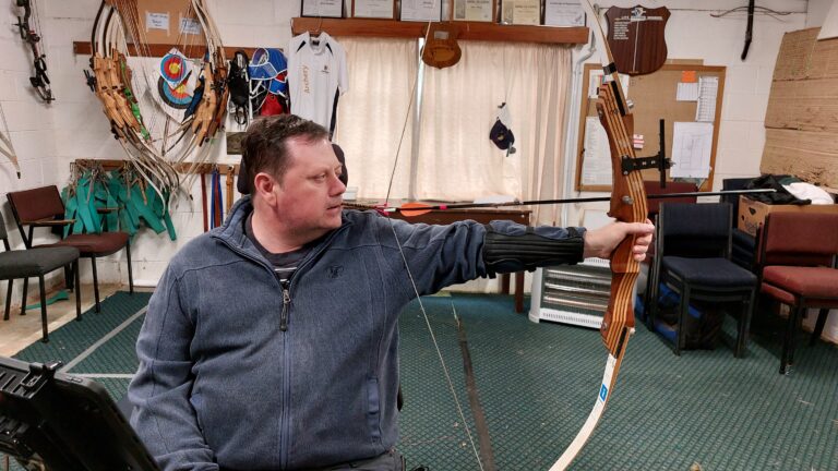 Paul Wallace holds raises his bow as he trains in Para archery