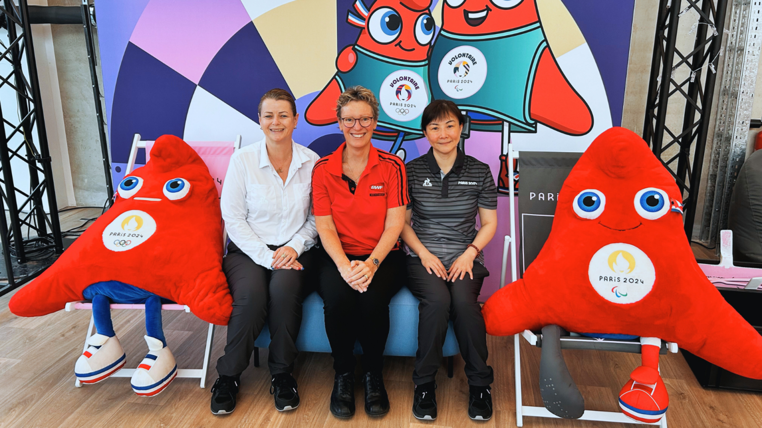 The three kiwi officials sit in front of a Paris 2024 Paralympic Games backdrop. L-R is Trish Gubb, Julie Carrel and Renee Yi Cui.