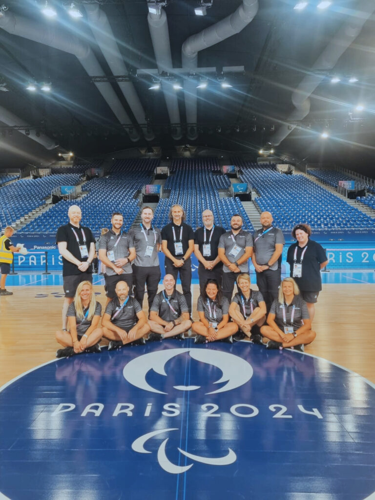 A group of Wheelchair rugby officals stand on the indoor court at the Paris 2024 Paralympic Games.