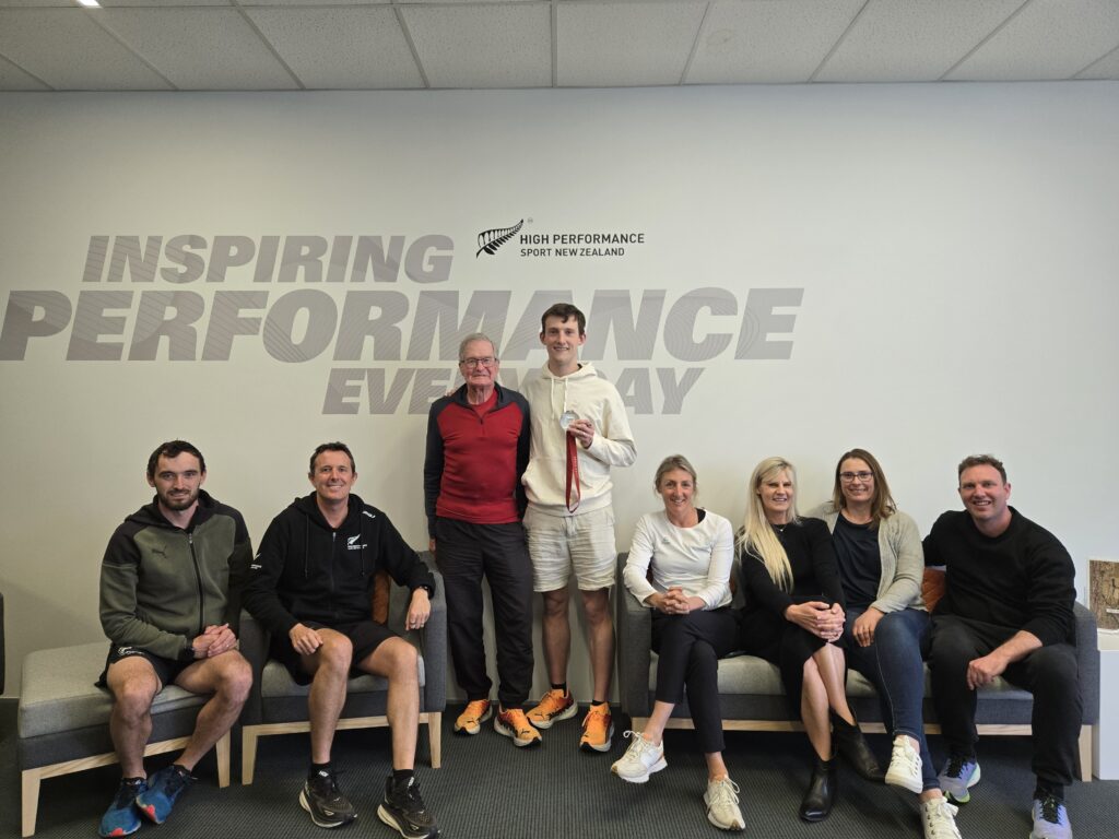 William Stedman stands with his support team at High Performance Sport New Zealand.