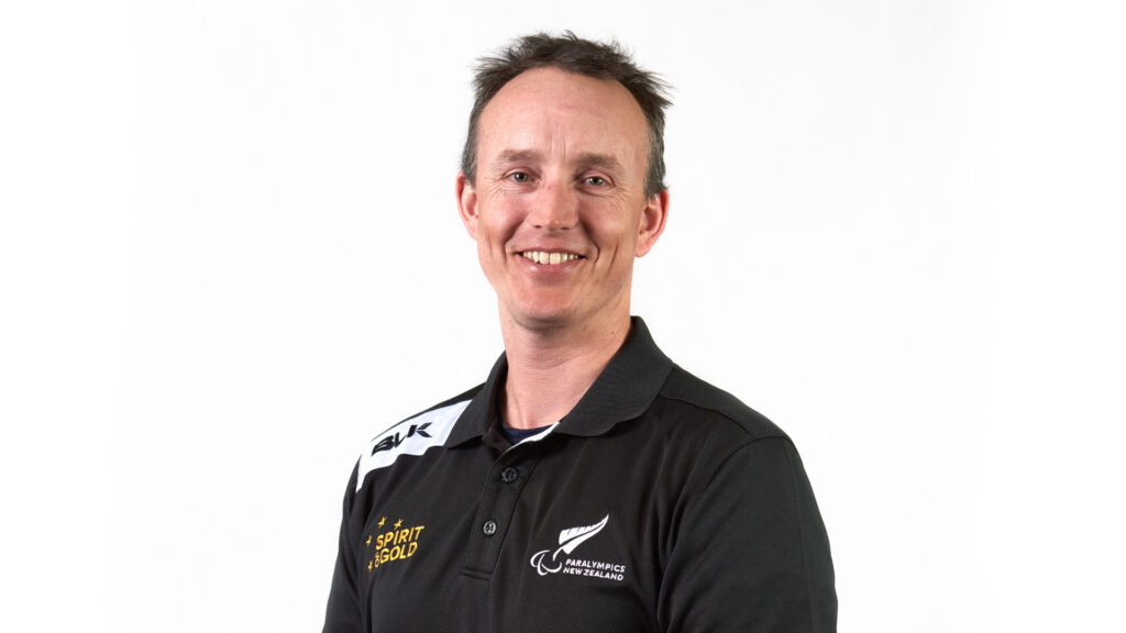 A Portrait of Paralympian #189 Carl Murphy on a white background. He wears a black NZ Paralympic Team uniform.