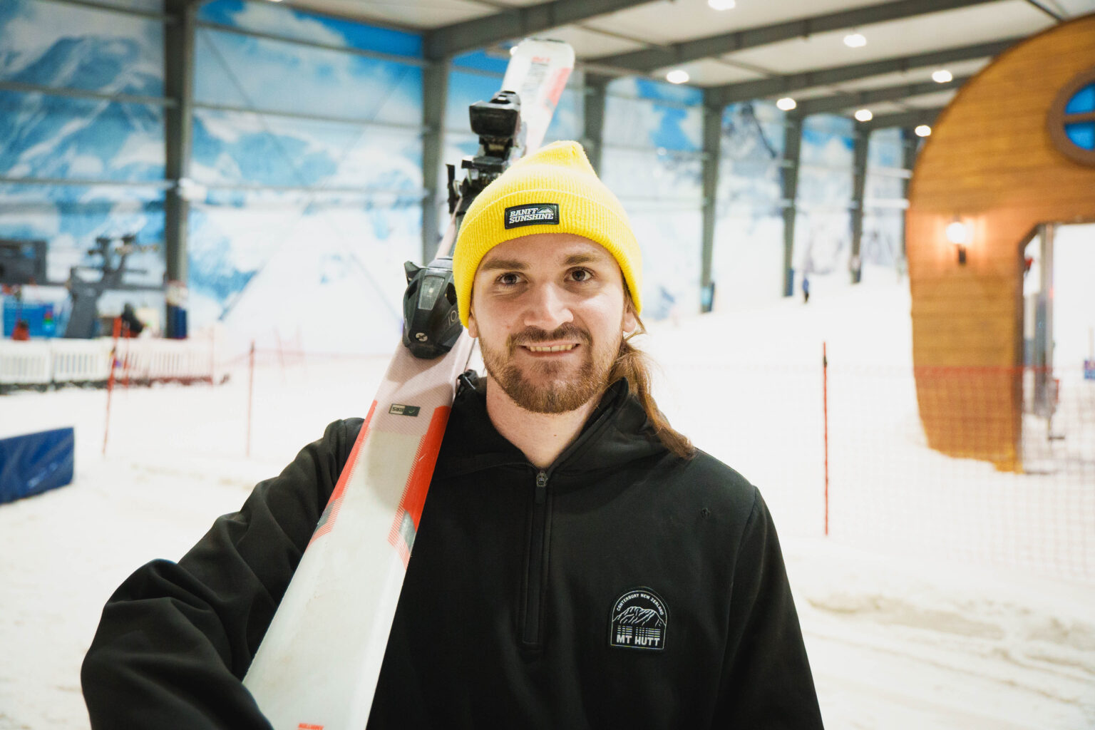 A portrait of Thomas Coysh holding a pair of ski's on a ski slope.