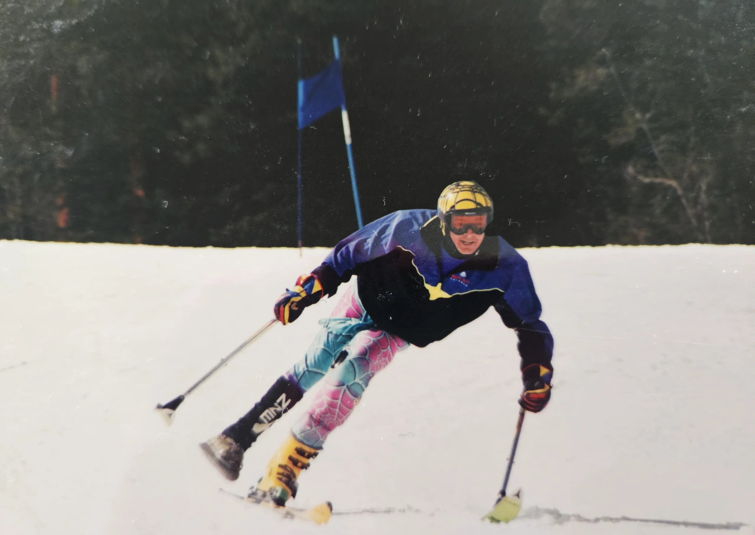 Kevin skis down a snowy mountain wearing vibrant colours.