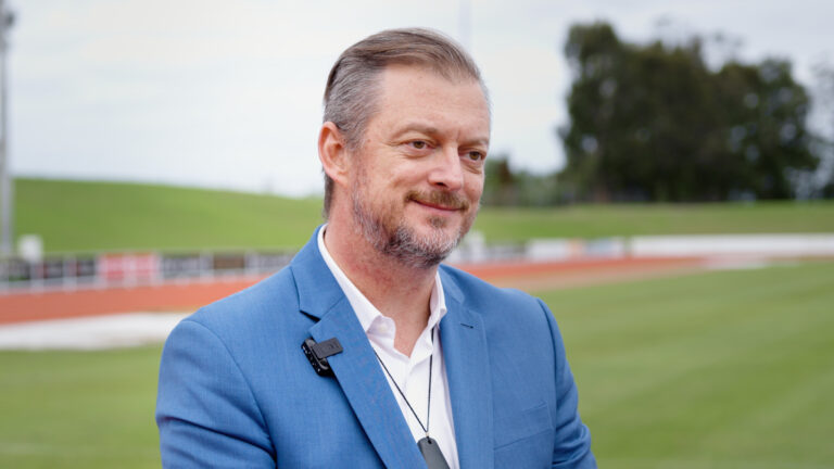 Andrew Parsons smiles on the infield of an athletics track.