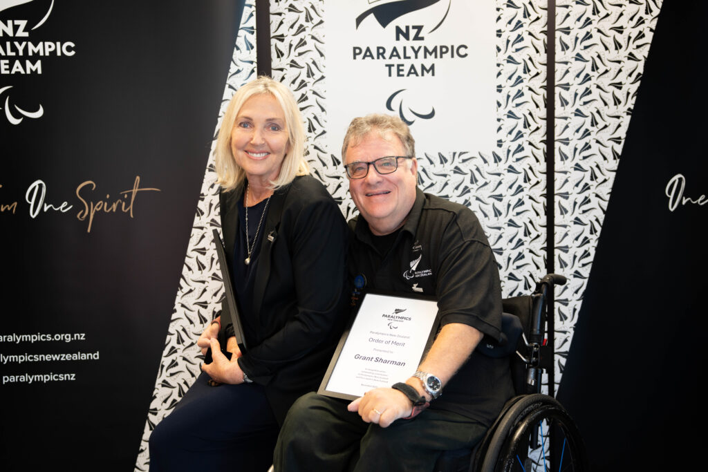 Order of Merit recipient Robyn Scott-Vincent sat on the left on the edge of the wheelchair of Grant Sharman, who is also pictured.