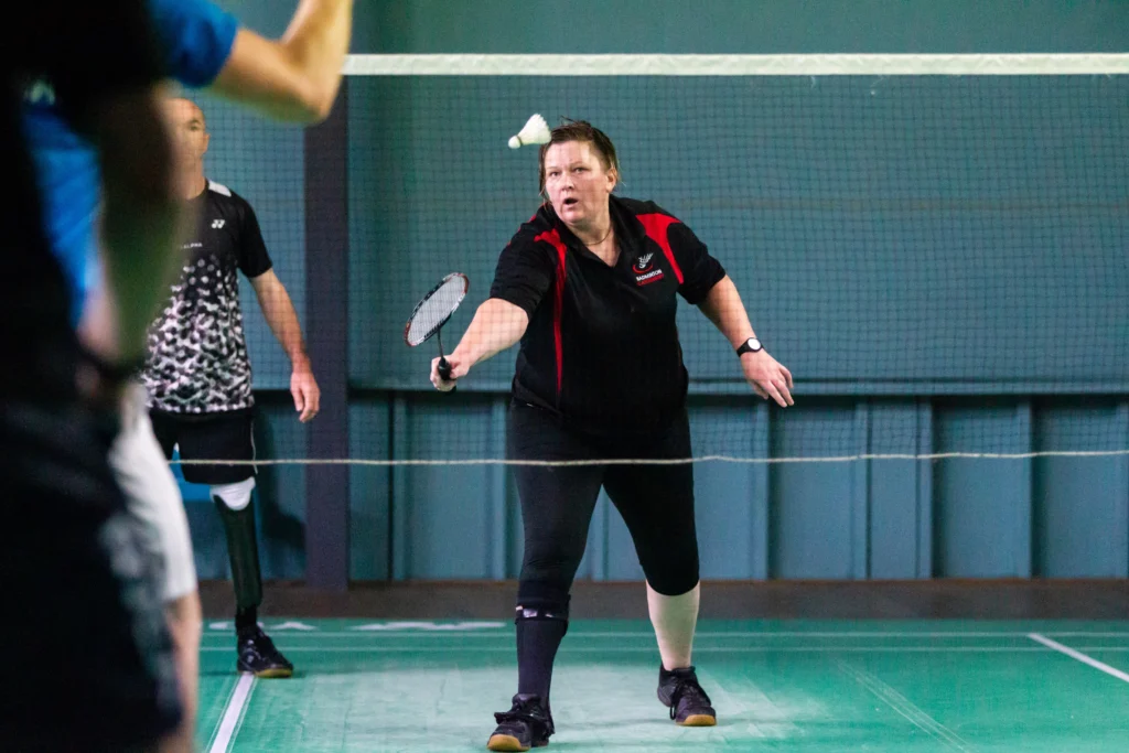 Carrie swings a racquet as a shuttlecock flies through the air.