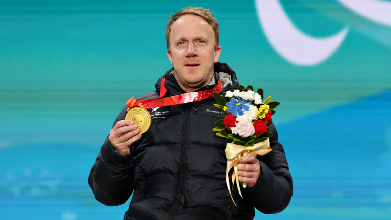 Paralympian #188 Corey Peters celebrates his gold medal at Beijing 2022 wearing a Macpac jacket.
