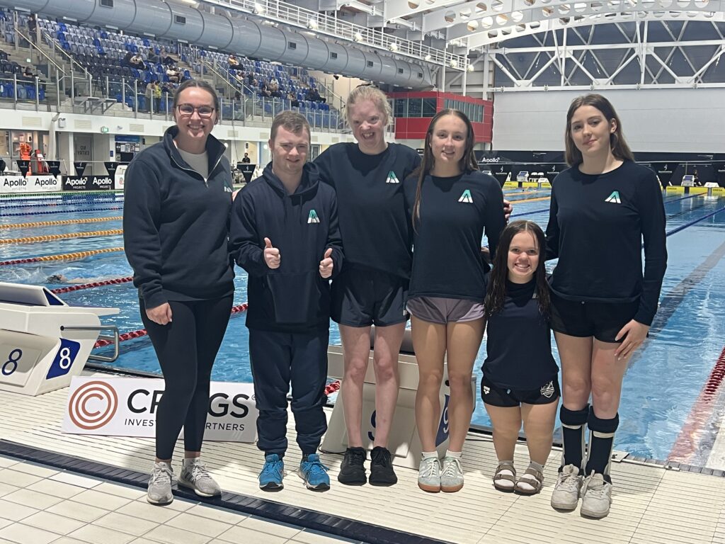 Emma Smith stands with her Para athletes next to a swimming pool.