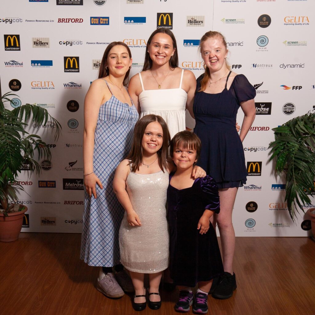 Emma Smith stands with Para athletes in front of an awards night backdrop.