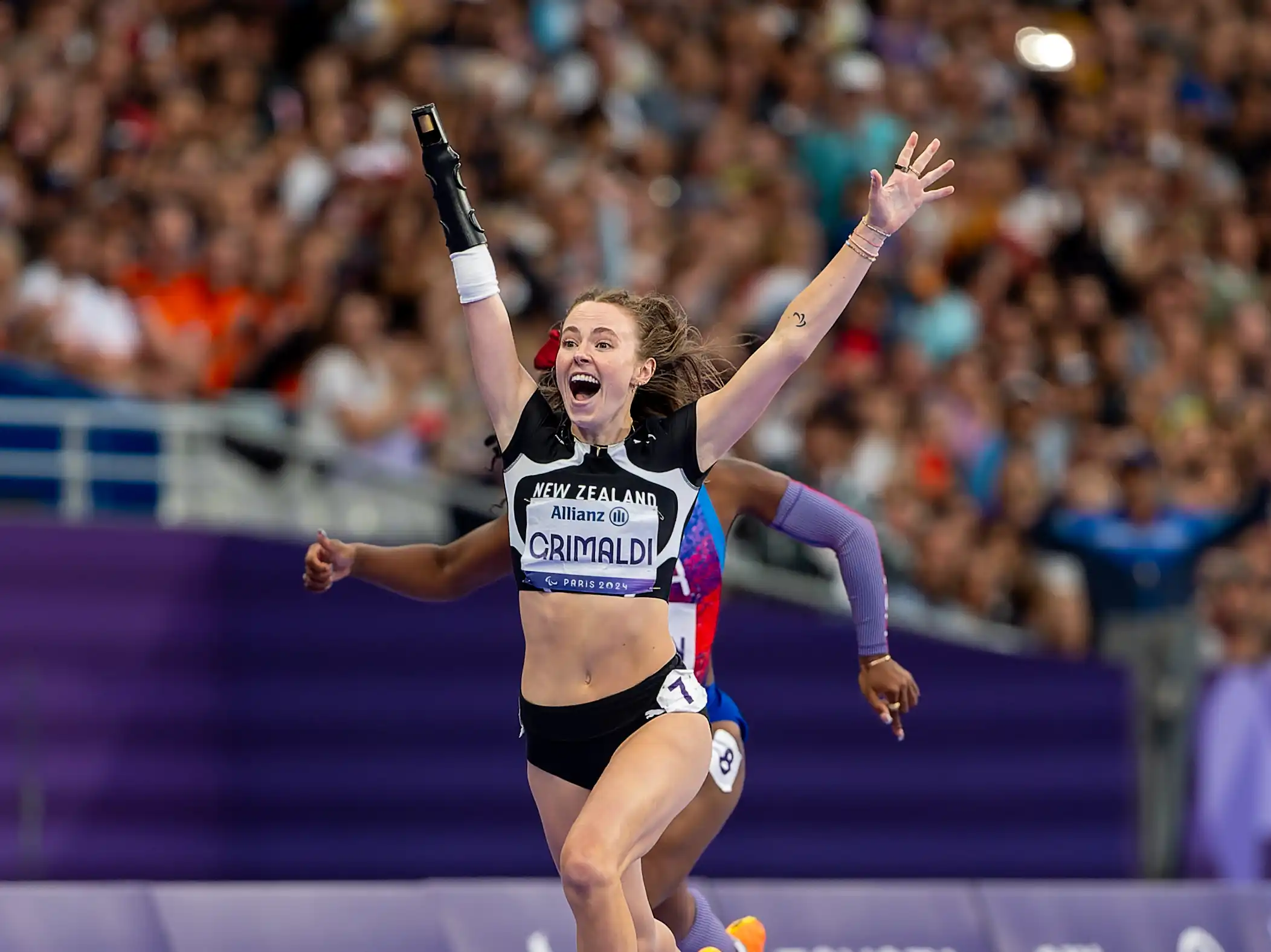 Paralympian #195 Anna Grimaldi runs across the finish line at the Paris 2024 Paralympic Games.